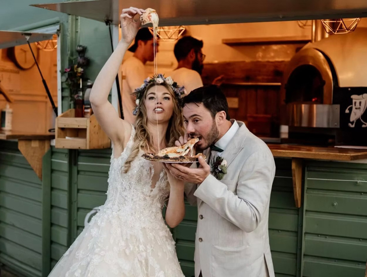 Bride and groom eating pizza in front of Dough Man's Land horsebox